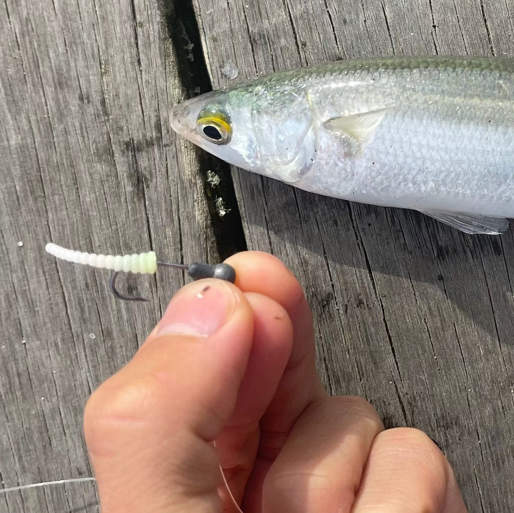 Fishing lure held by a hand on a wooden surface